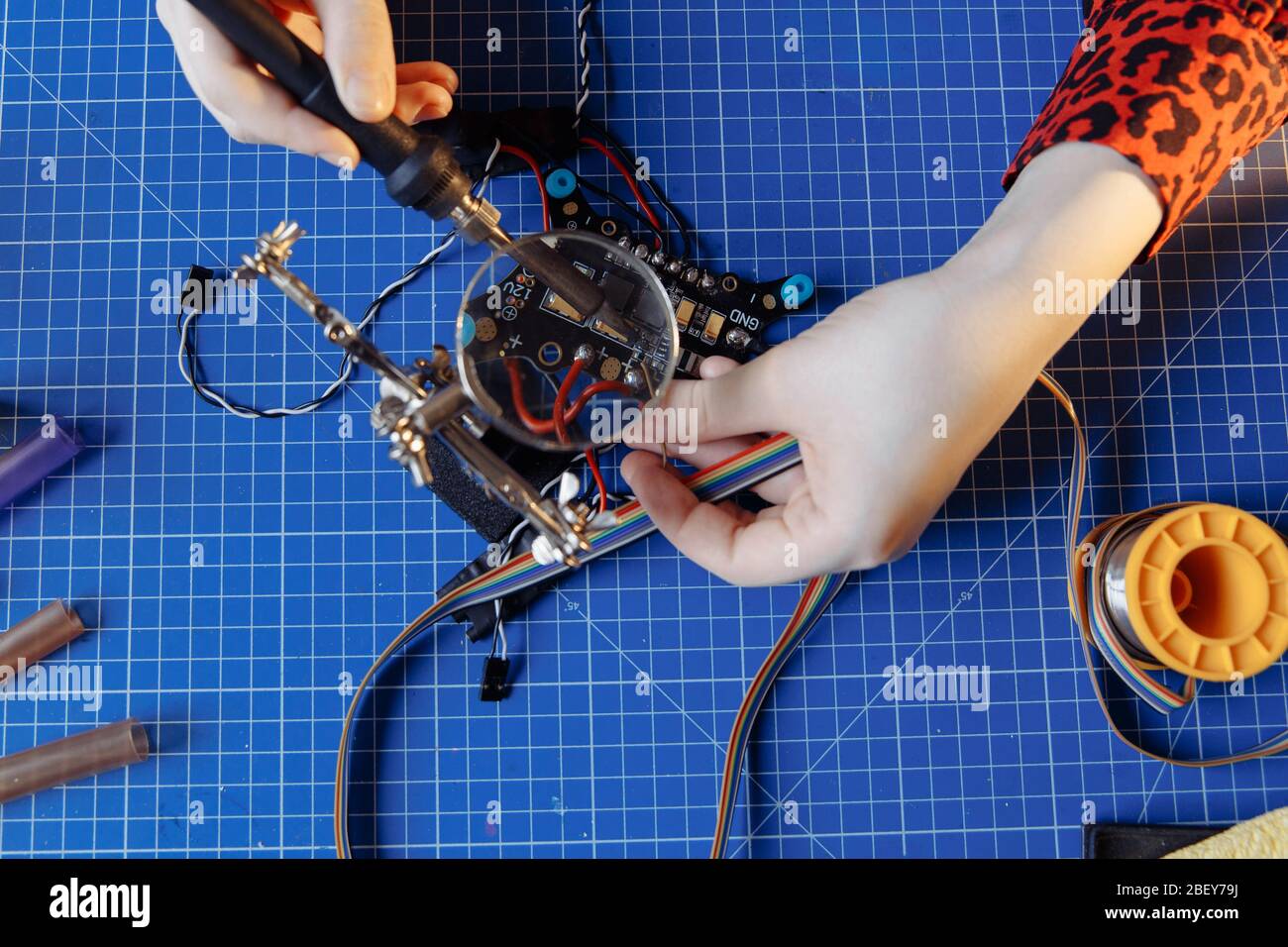 Top view of the soldering process. Hands hold the soldering iron and