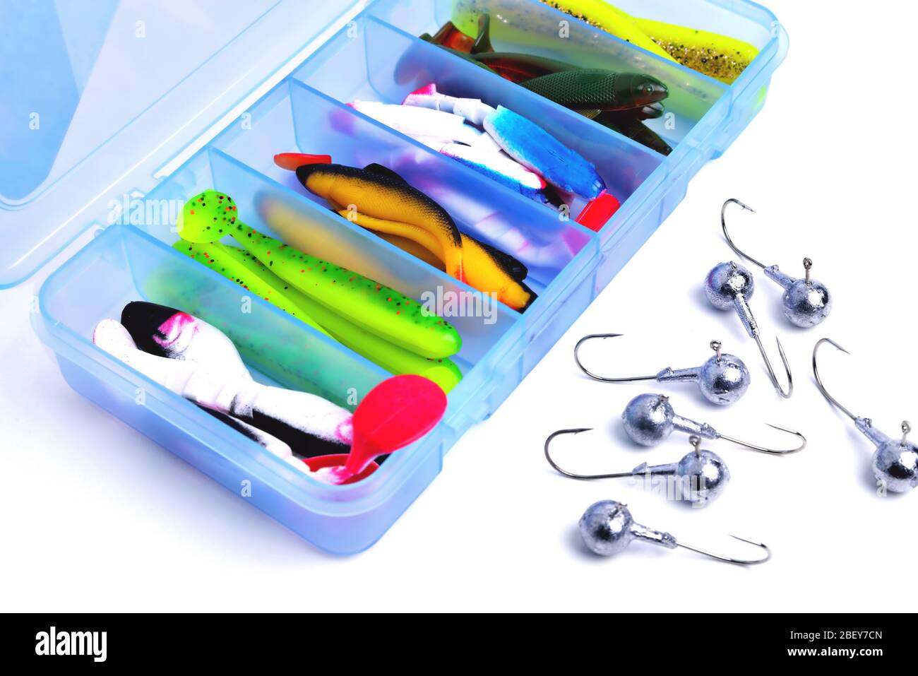 Box for fishing accessories with silicone baits inside, Jig hooks on a white background close-up Stock Photo