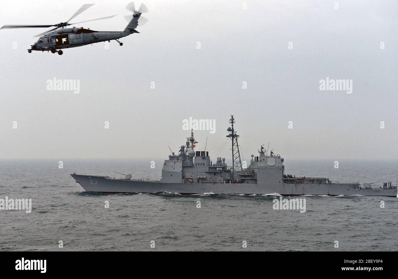 (Jan. 29, 2013) An MH-60S Sea Hawk helicopter from the Eightballers of Helicopter Sea Combat Squadron (HSC) 8 flies by the Ticonderoga-class guided-missile cruiser USS Mobile Bay (CG 53) during a replenishment-at-sea. Mobile Bay, assigned to the John C. Stennis Carrier Strike Group, is deployed to the U.S. 5th Fleet area of responsibility conducting maritime security operations, theater security cooperation efforts and support missions for Operation Enduring Freedom. Stock Photo