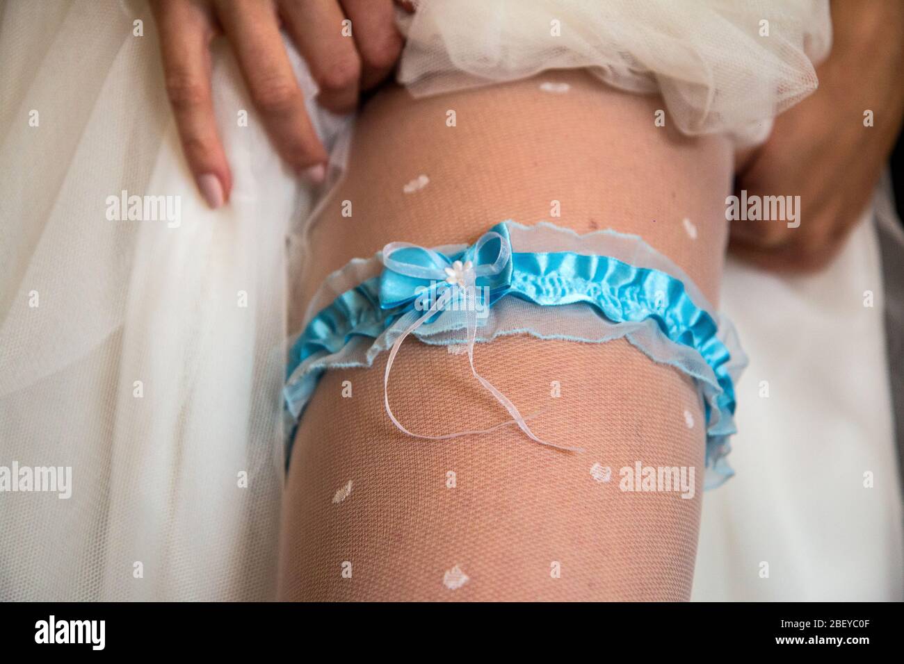 The detail of the leg of a bride. She wears the traditional wedding garter under her wedding dress. Stock Photo