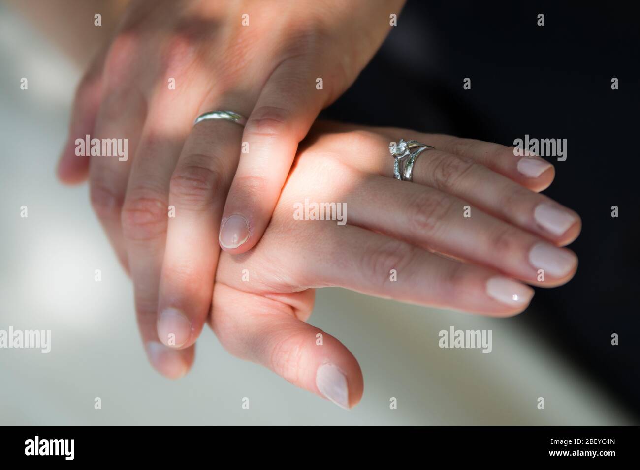 The young couple is holding their hands after the wedding ceremony and showing their new rings symbolising their love. Stock Photo