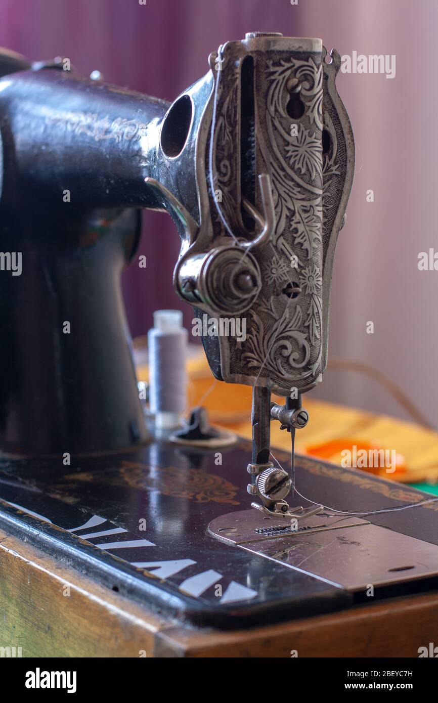 Old retro sewing machine with a needle and inserted white thread. Clamp