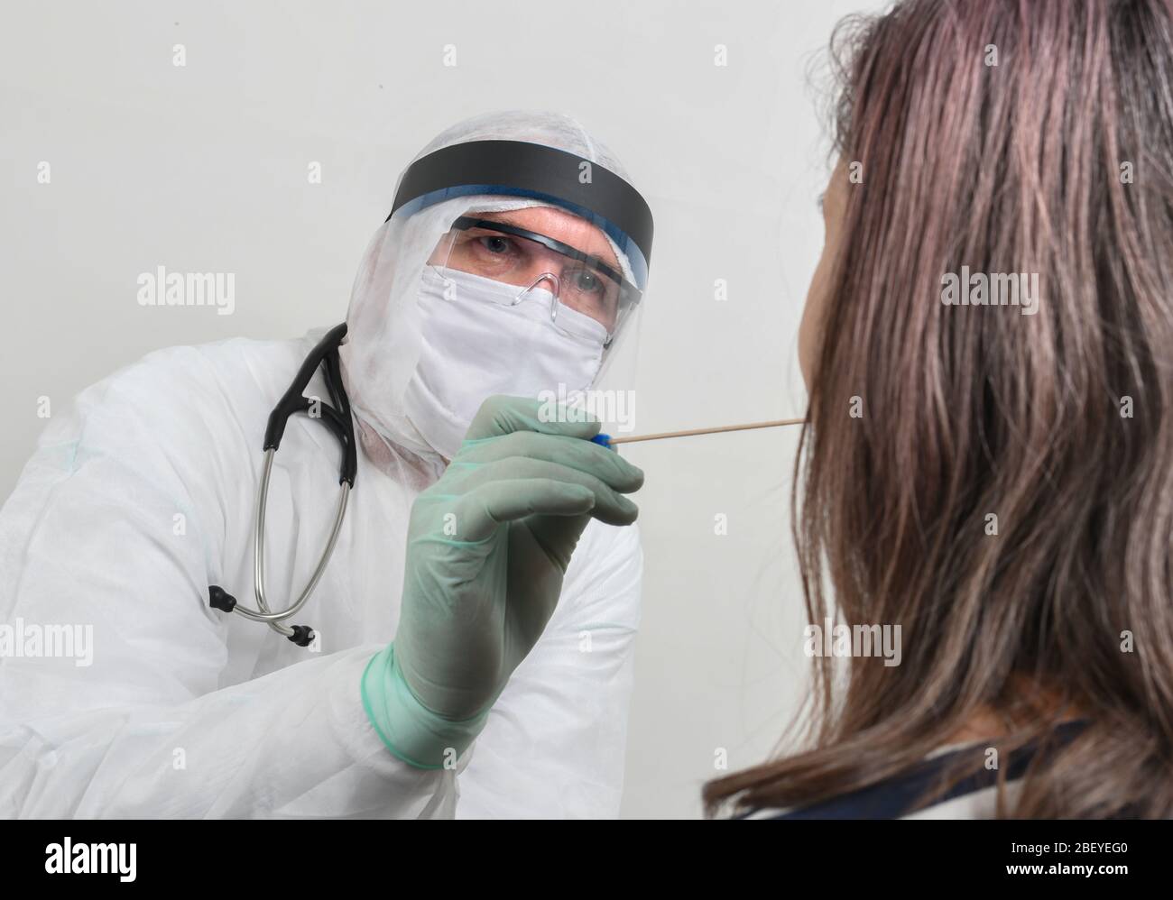 Male doctor examining her female patient with stick to make swab test ...