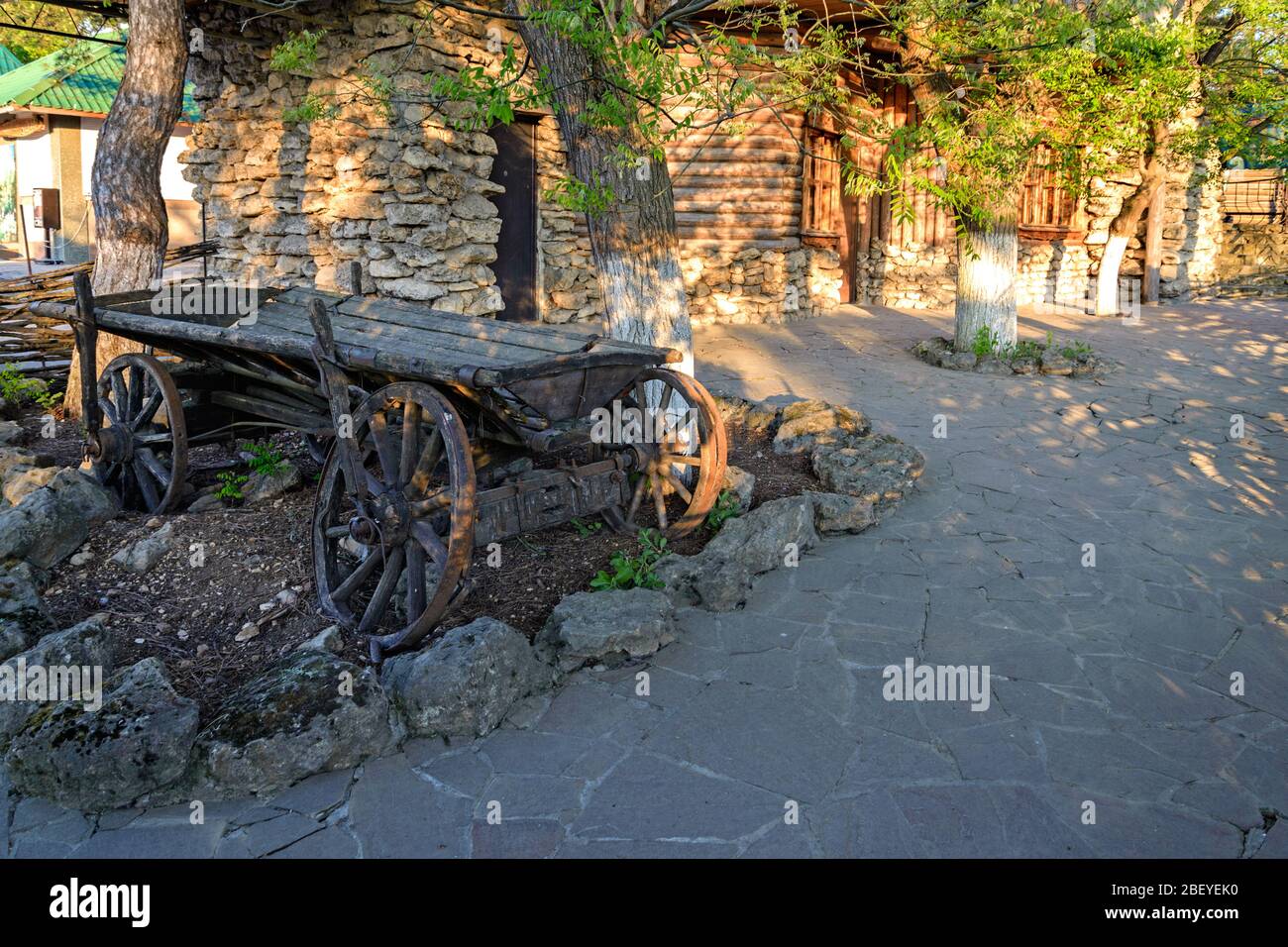 An old cart stands  in front of a stone house Stock Photo