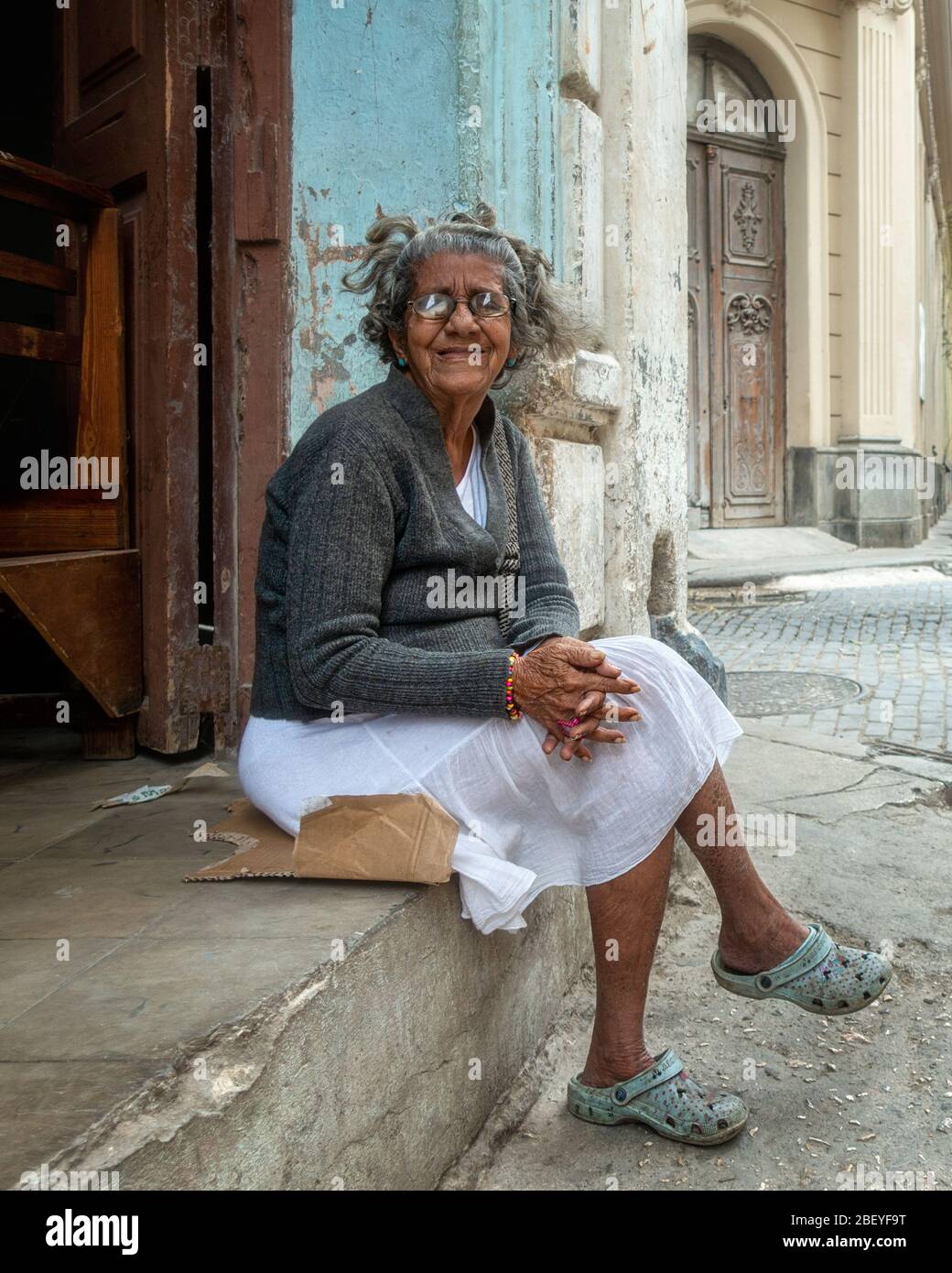 Senior woman sitting on a Havanan street in old town Havana with thick lens spectacles and poor eyesight, but seemingly content, Cuba Stock Photo