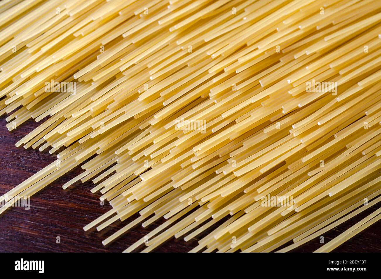 Raw spaghetti background. Unprepared spaghetti on a dark wooden table ...