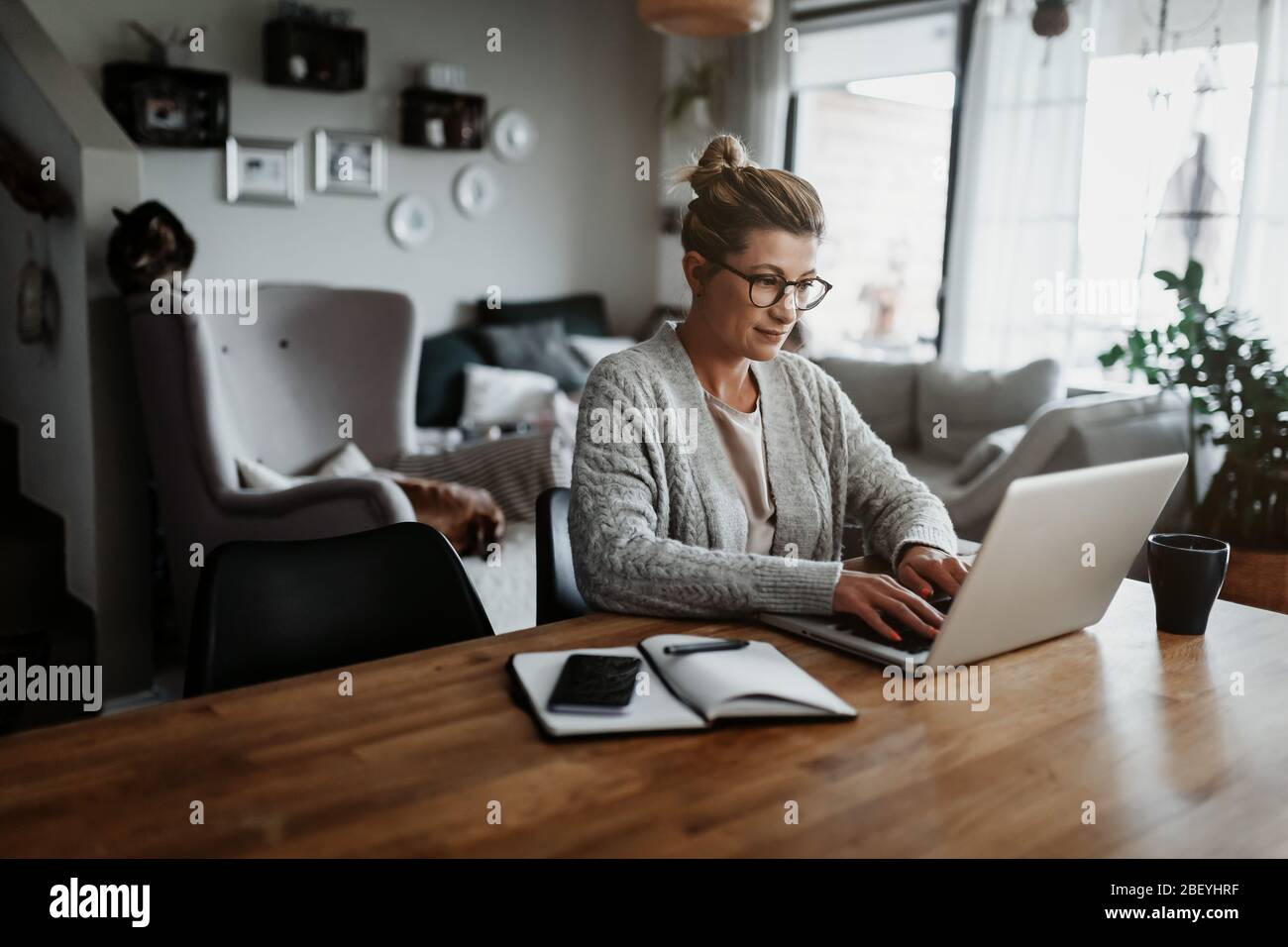 Businesswoman working on laptop computer sitting at home and managing her business via home office during Coronavirus or Covid-19 quarantine Stock Photo