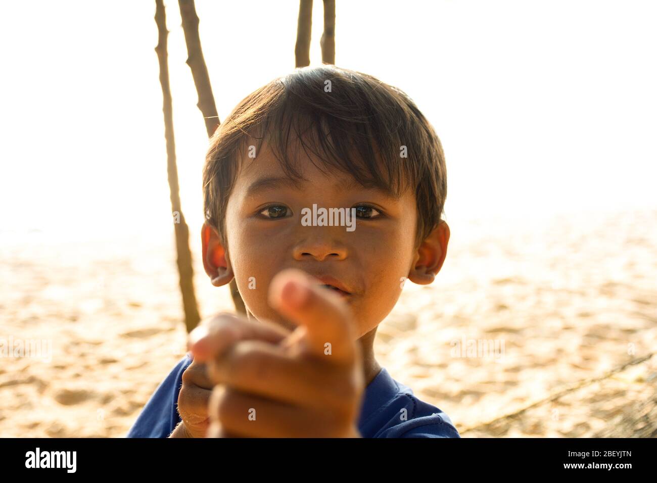 A young local boy from Cambodia, playfully looking and pointing at the camera. Stock Photo