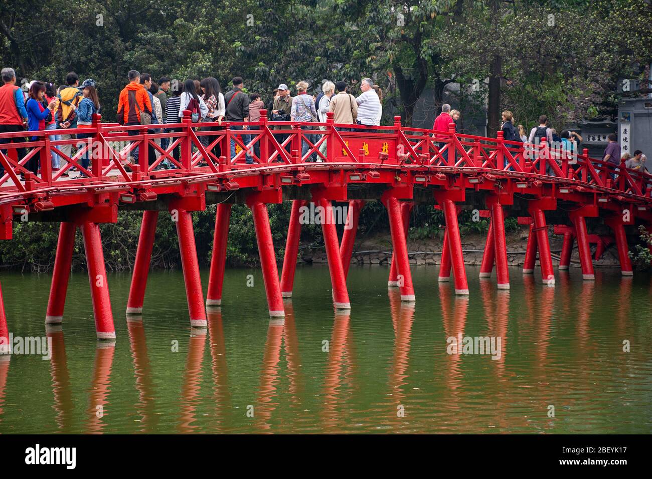 The Huc Bridge (Red Chinese Bridge) full of tourists visiting the Ngoc Son Temple in Hanoi, Vietnam. Stock Photo