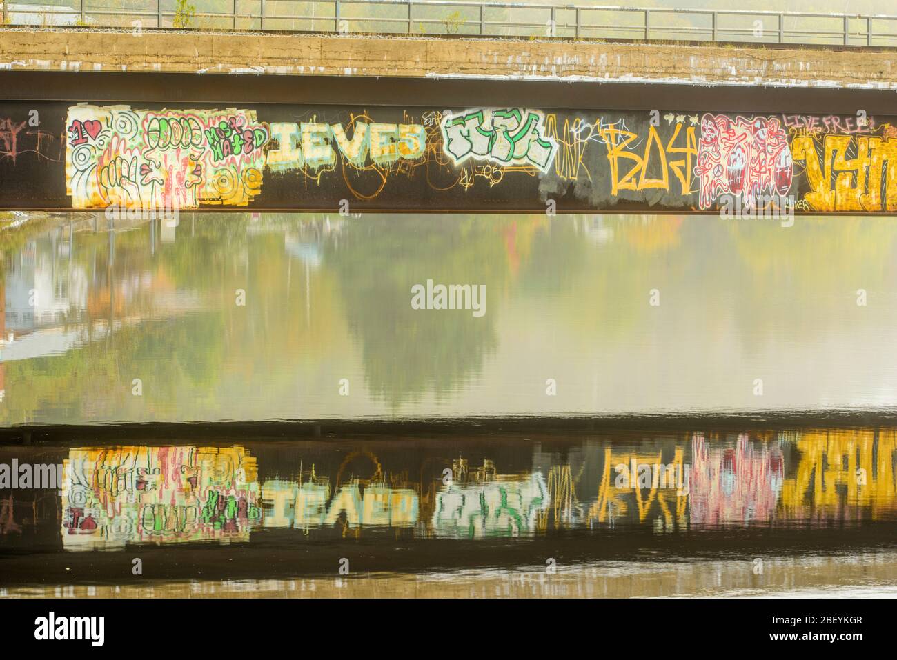Graffiti on a rail line bridge reflected in the Wanapitei River, Greater Sudbury, Wahnapitae, Ontario, Canada Stock Photo