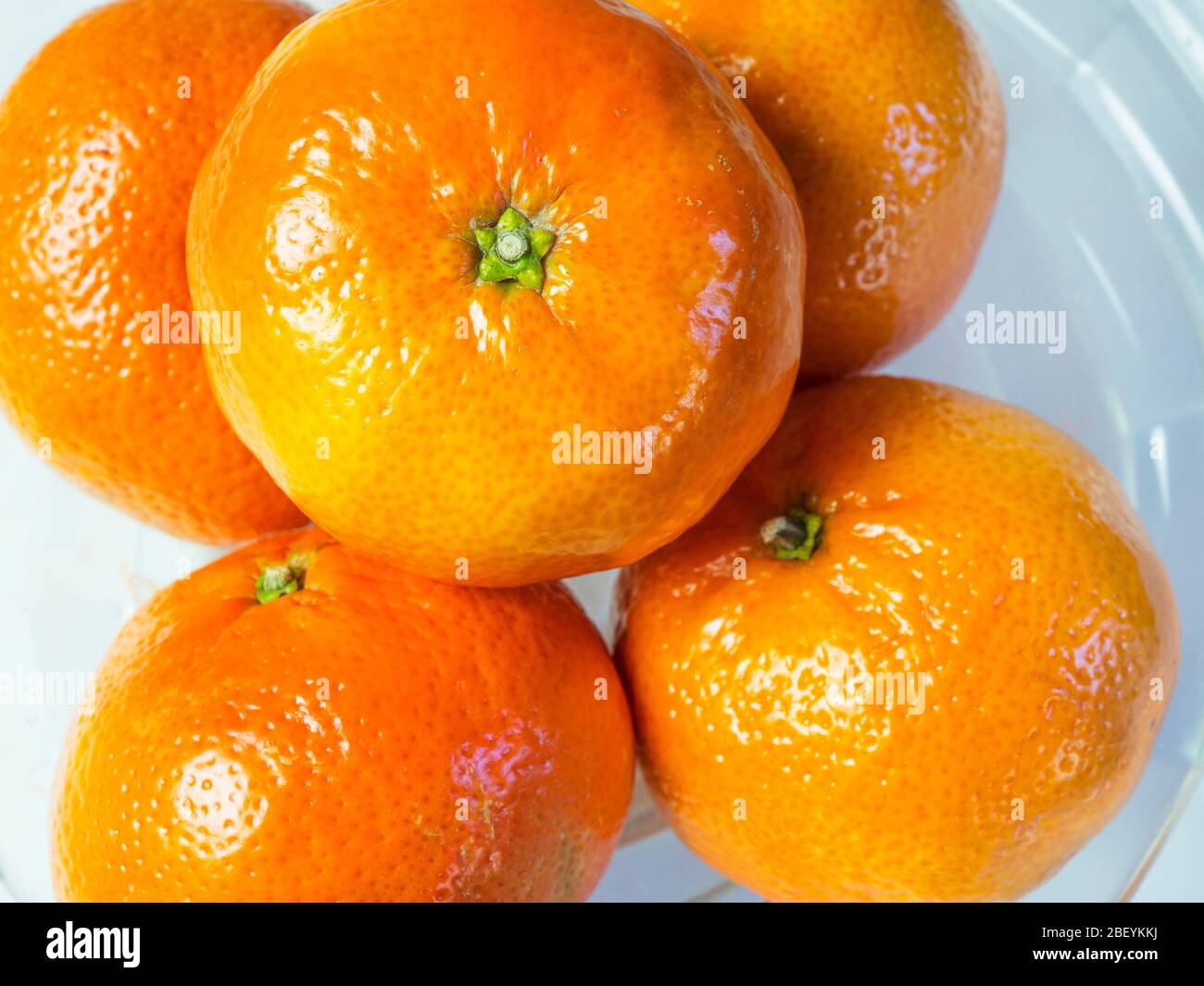 Easy peeler mandarin oranges in a glass bowl on a white background