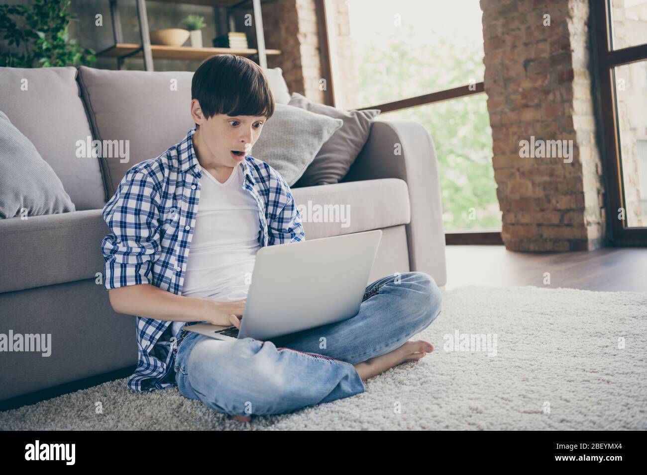 Photo of teenager school boy sit floor carpet near couch barefoot legs  crossed stay home quarantine hold notebook online education big homework  email Stock Photo - Alamy