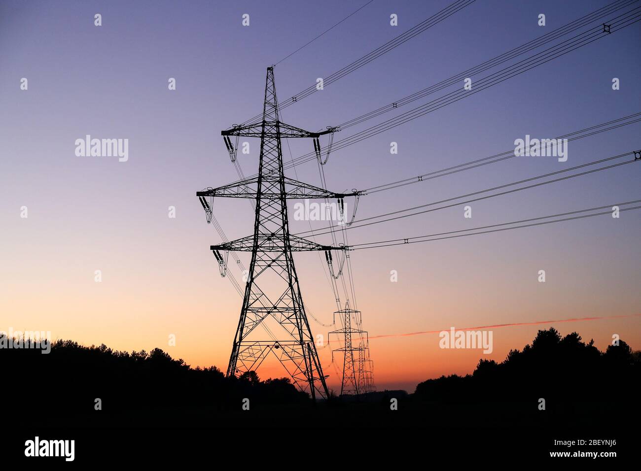 Row of electricity pylons at sunset. Stock Photo