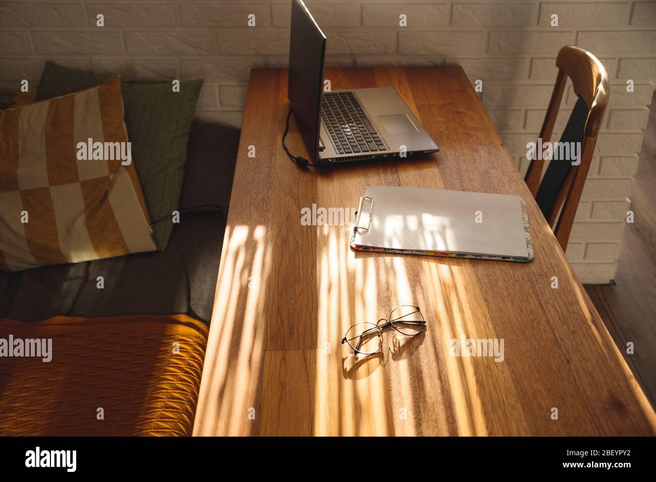 Minimalistic workplace at home on a wooden table in the shadows. Stock Photo