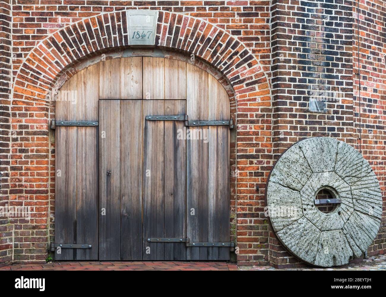 Wooden door and old mill stone, Jever windmill, Friesland, Lower Saxony, Germany Stock Photo