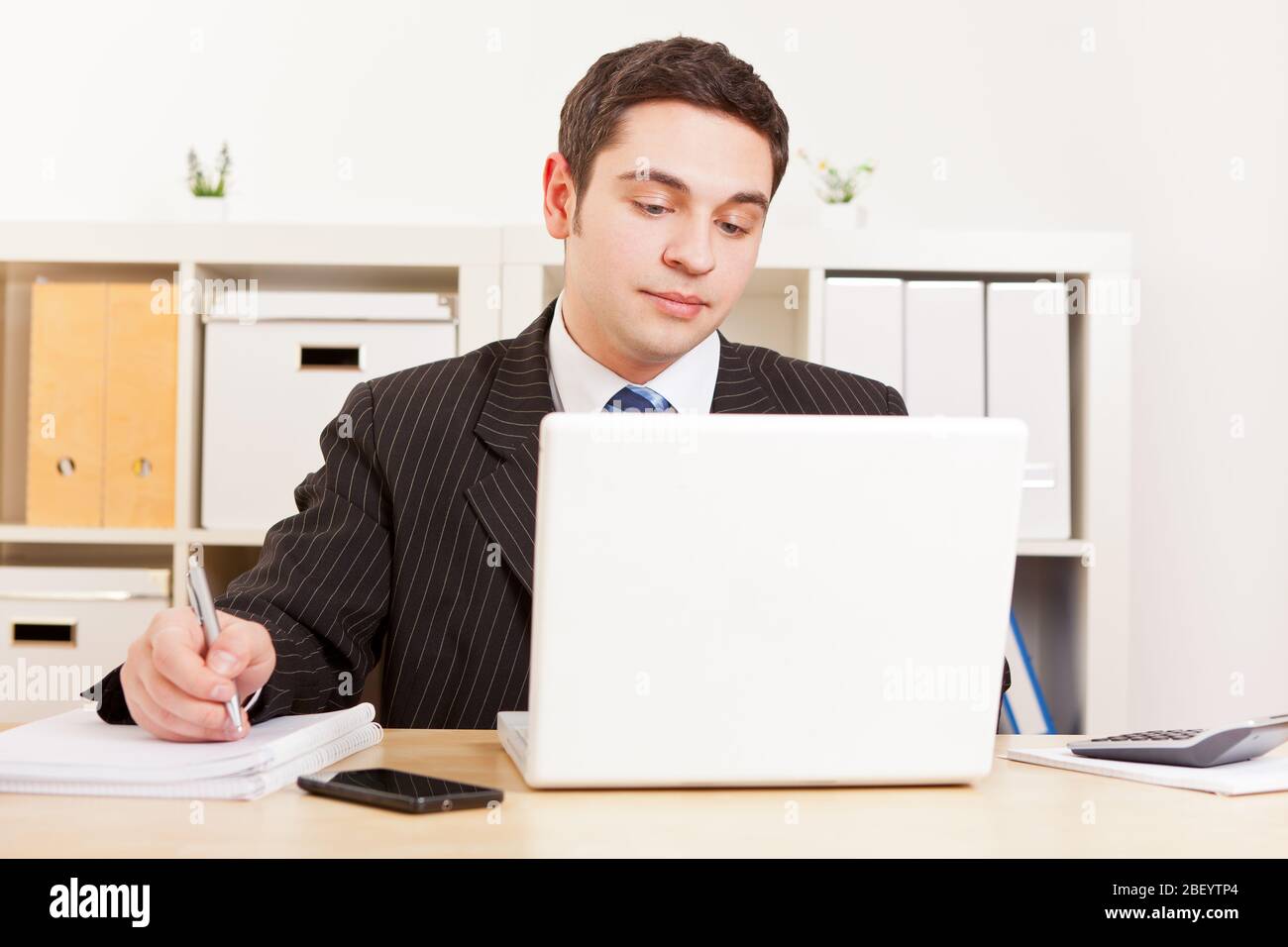 Young businessman in a suit works on the computer Stock Photo