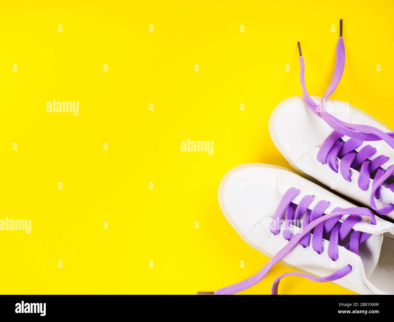 White sneakers with purple laces on yellow background Stock Photo - Alamy