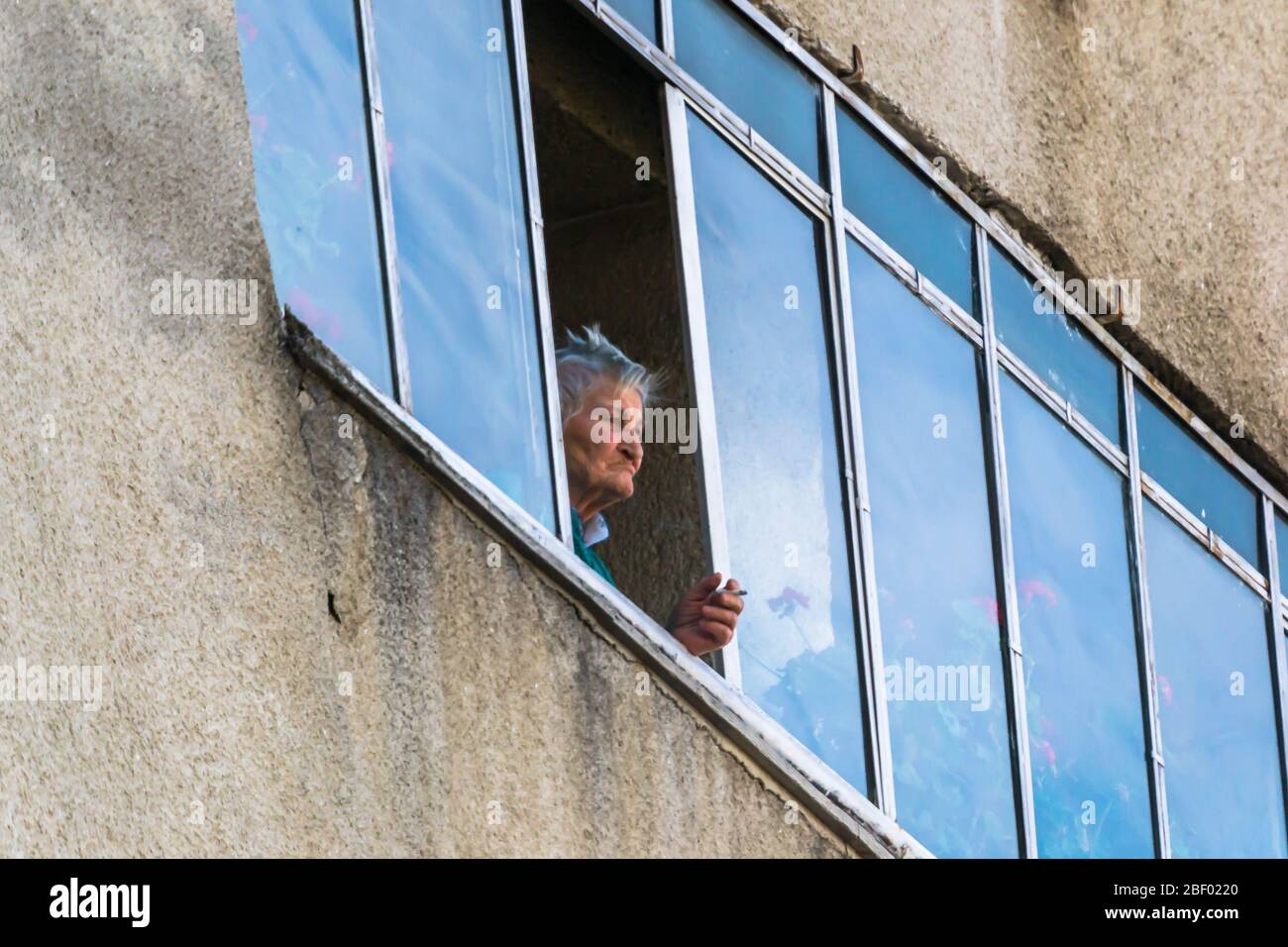 old women  smoking cigarettes on her balcony and thinking Stock Photo