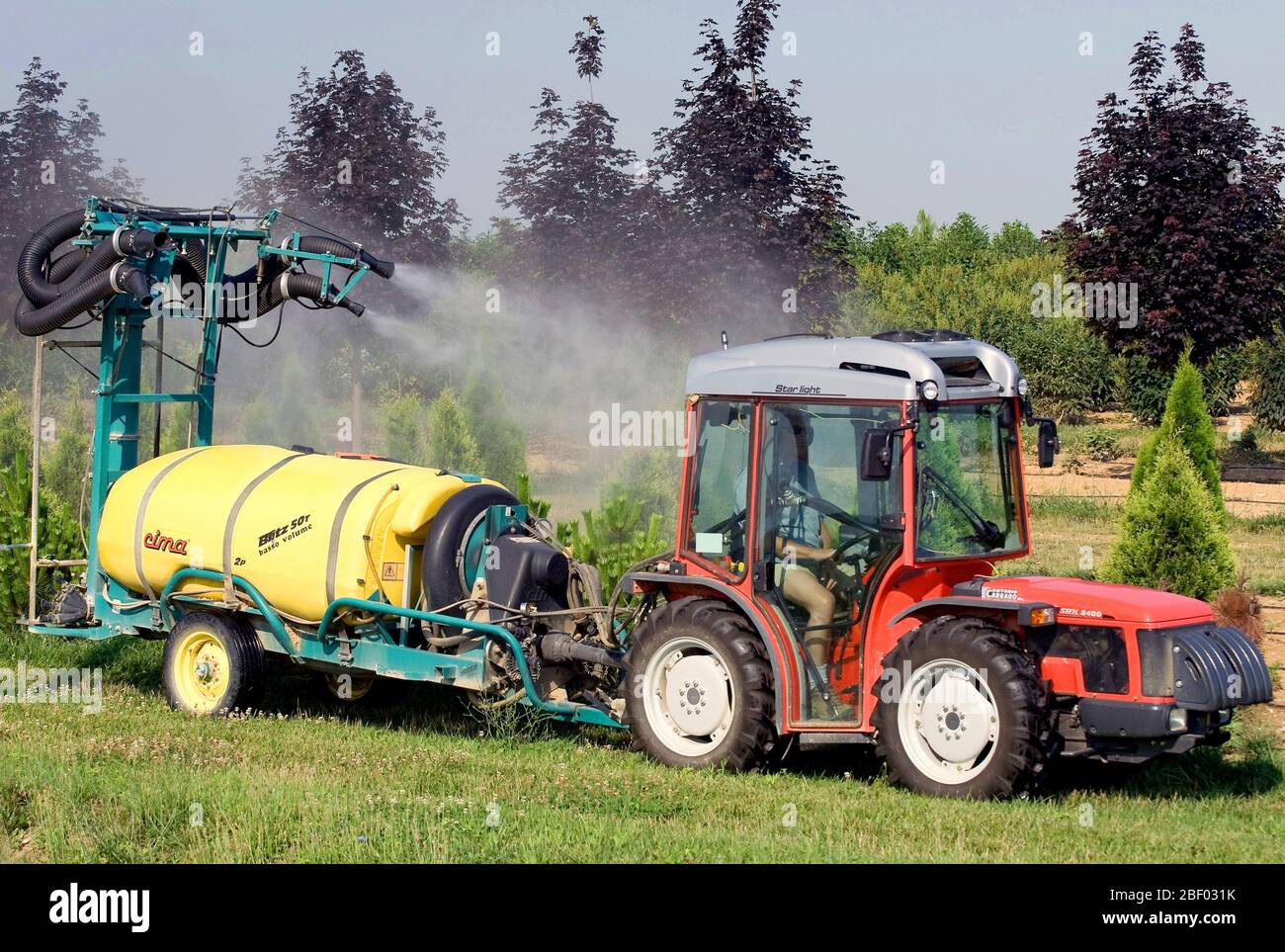 2008 - Farmer driving an Antonio Carraro SRX 8400 tractor and pulling a pesticide sprayer spraying trees on a tree farm (orchard) Stock Photo