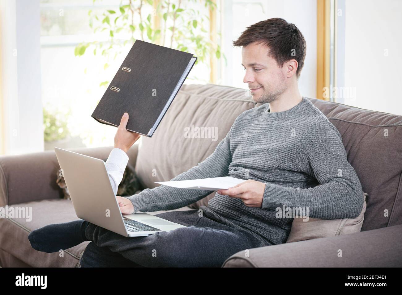 Working from home - man gets files handed to him through the laptop screen Stock Photo