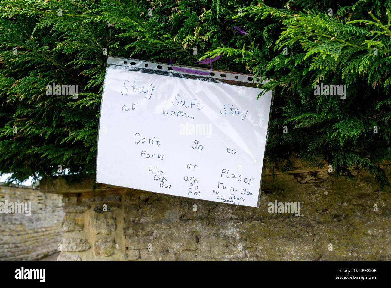Chippenham, Wiltshire UK, 16th April, 2020. With the nation due to once again clap to show their support for the NHS tonight, a childs handwritten sign telling people to stay in and stay safe is pictured on a hedge in Chippenham, Wiltshire. Credit: Lynchpics/Alamy Live News Stock Photo