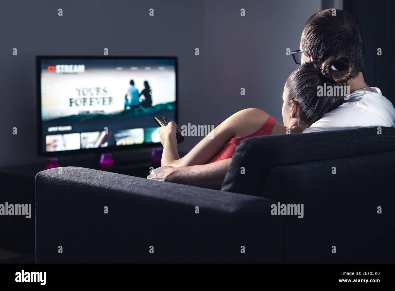 Movie stream service on smart tv. Couple watching series online. Woman choosing film or new season with remote control. Video on demand (VOD) site. Stock Photo