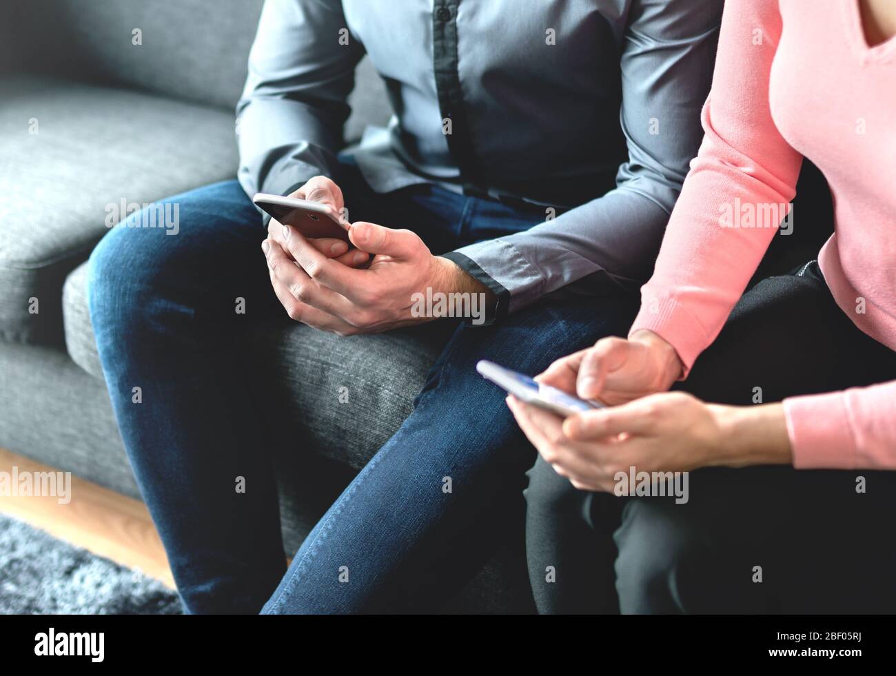Two people using mobile phones. Business partners, friends or couple looking at their smartphones. Man and woman exchanging numbers during meeting. Stock Photo