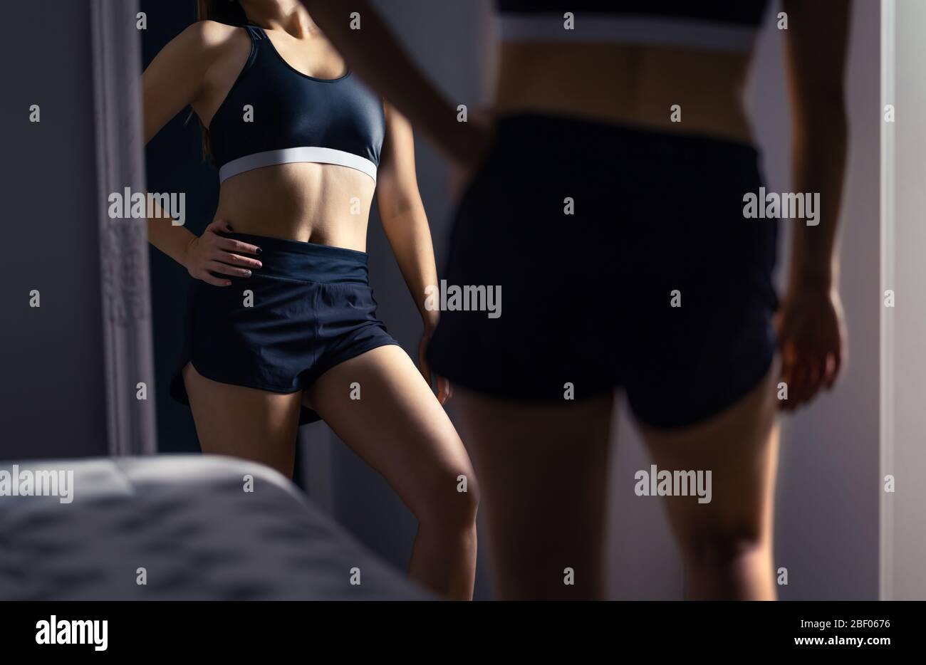 Progress and results in weight loss, workout, fitness or diet. Perfect healthy thin slim body. Fit woman looking herself in the mirror after exercise. Stock Photo