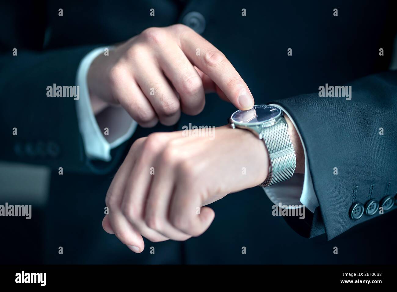 Watch around the wrist of a stylish business man. Busy businessman looking at the time. Stress or hurry at work. Person wearing suit. Stock Photo