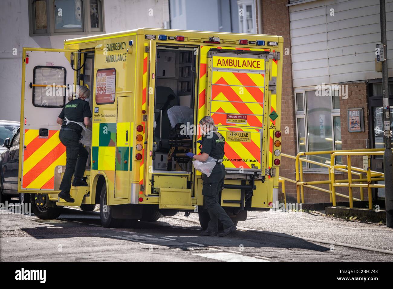Ambulance crew in full PPE prepare to enter a block of sheltered accommodation flats, central Brighton, East Sussex, UK Stock Photo