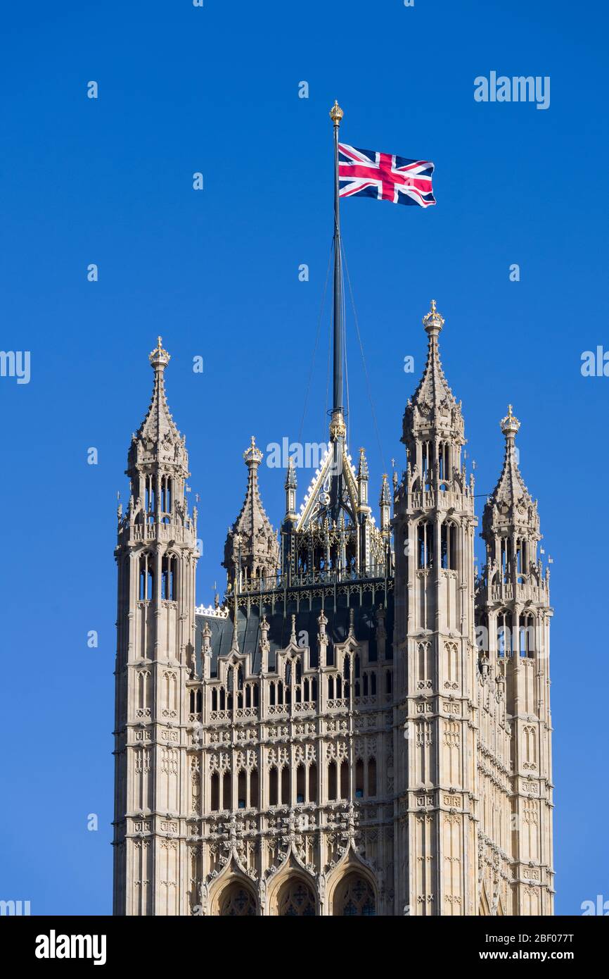 A Union Jack flag flying from, The Victoria Tower, Palace of Westminster commonly known as the Houses of Parliament, which is the meeting place of the Stock Photo