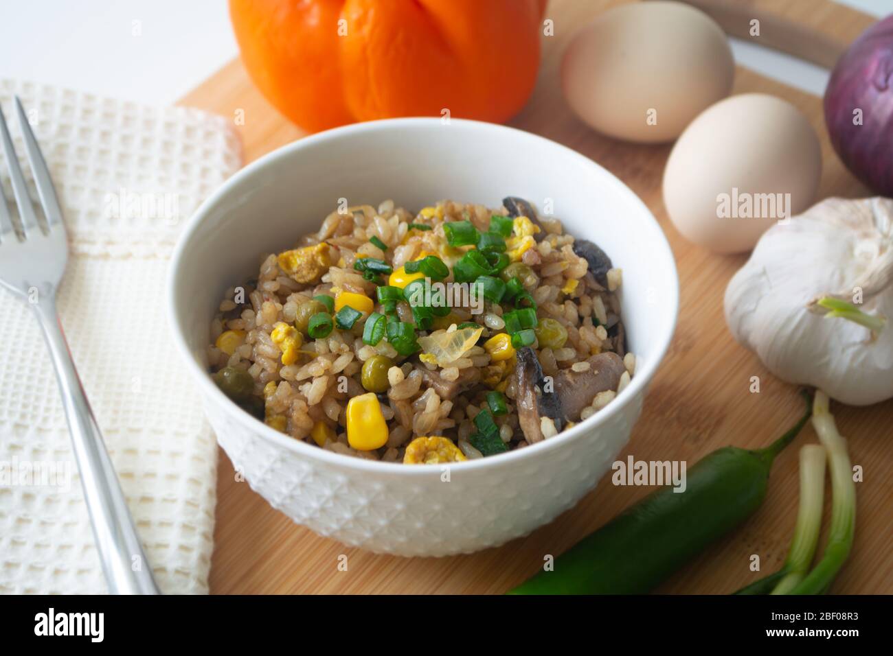 Chinese style vegetarian egg fried rice with sweet corn, green peas, onions, garlic, mushrooms and scallions Stock Photo