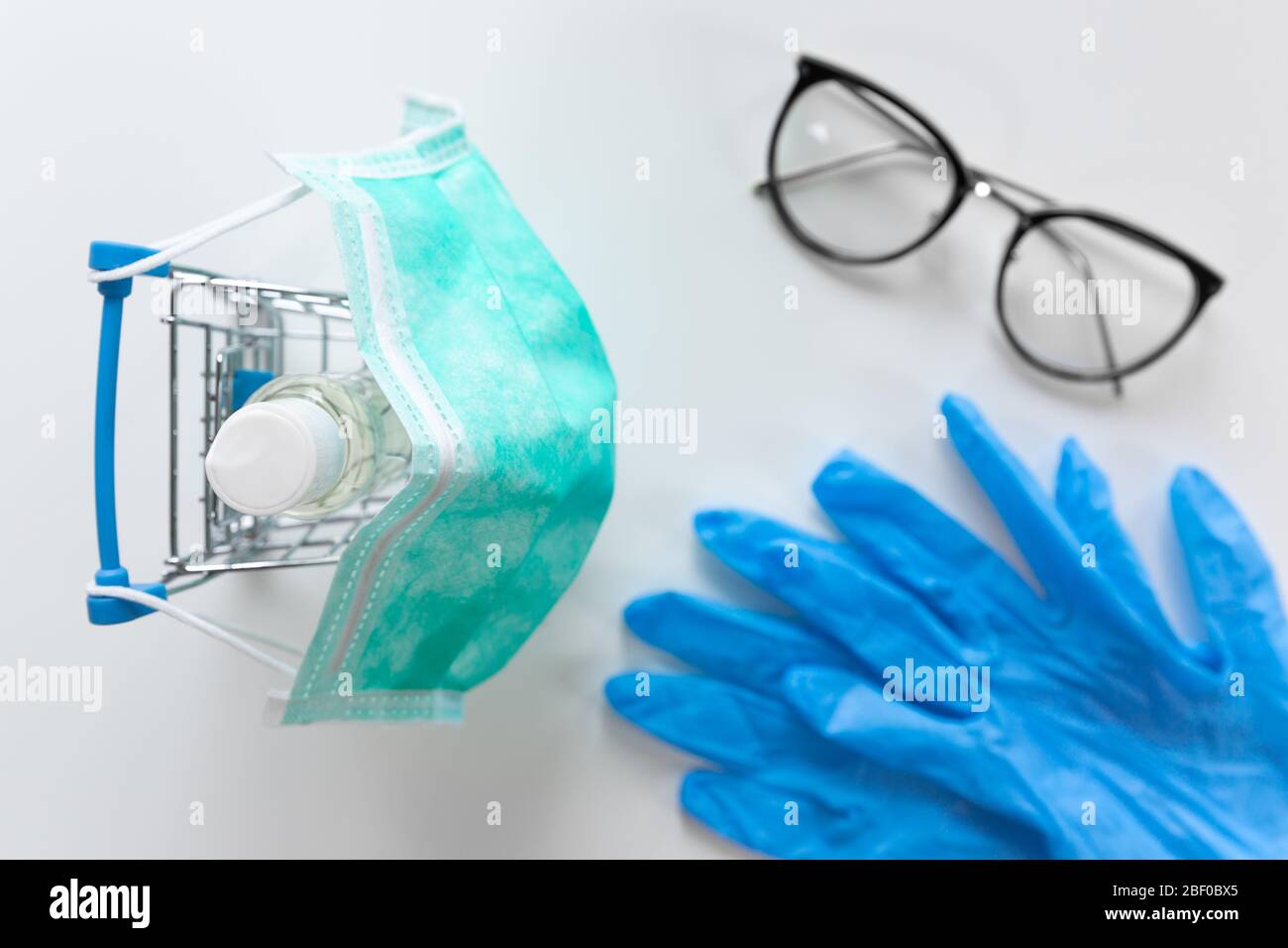 Shopping cart with facial mask hand sanitiser and blue gloves. Shopping and protection concept Stock Photo