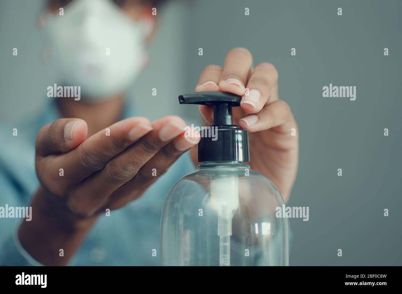 Selective focus on the hands of a black woman using sanitizer gel or ...