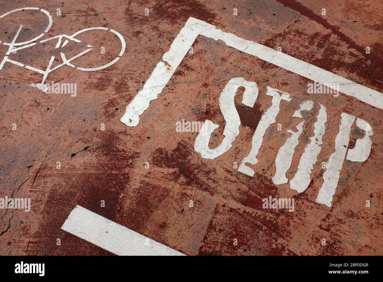 Old and fainted STOP word and a bicycle painted white on the grungy ground Stock Photo