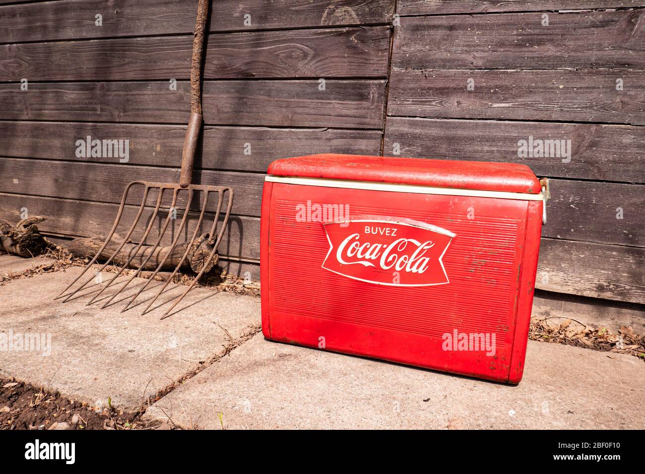 Vintage red classic french Buvez Coca Cola cooler from 1964. Dark retro rural farm setting. Stock Photo
