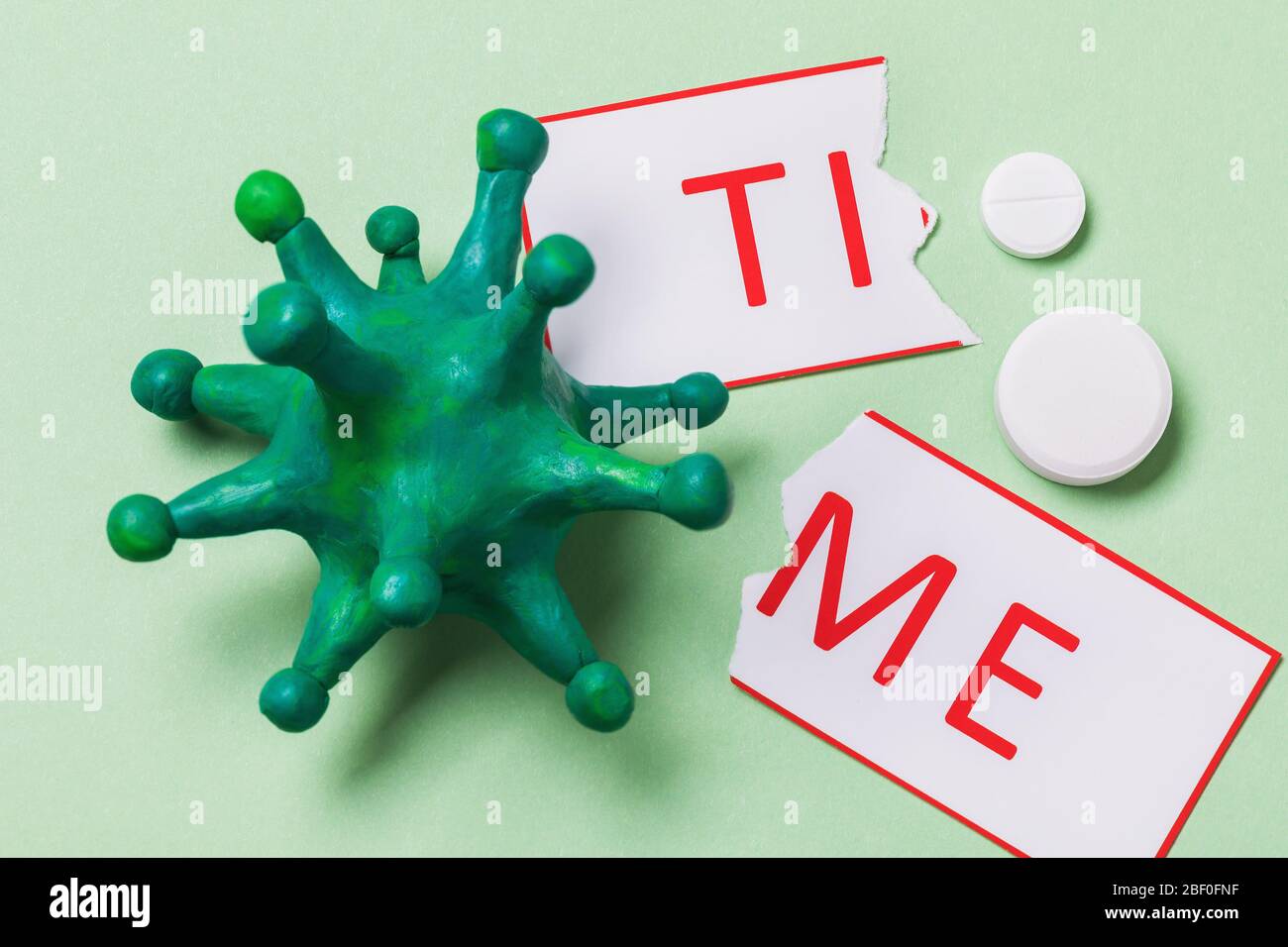 Toy coronavirus, torn tag with text and pills, top view. A concept on the topic of wasted time on pandemic treatment Stock Photo
