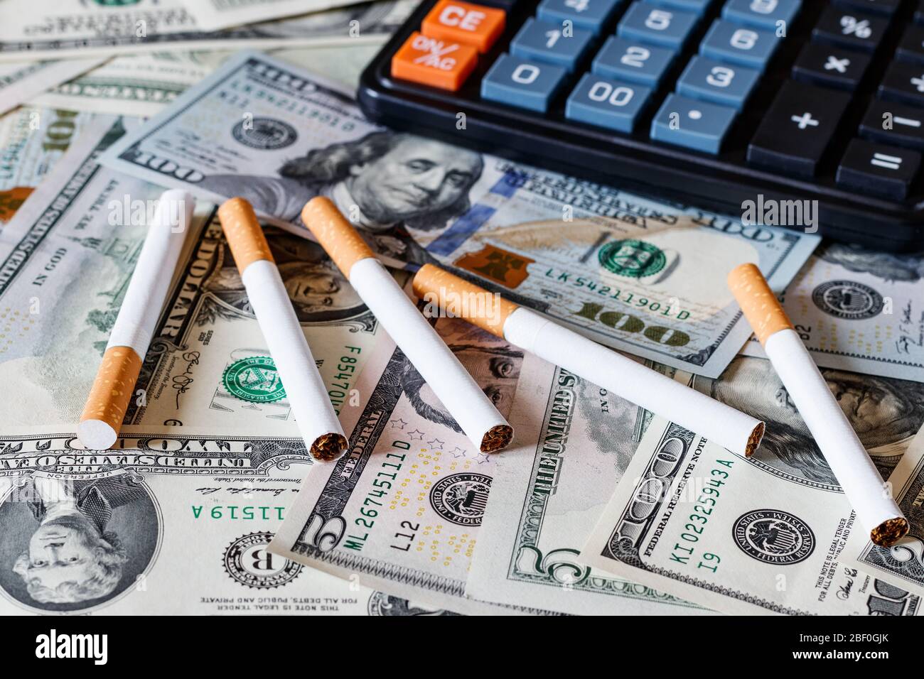 Concept of smoking cost. Cigaretes on a dollars background and black  calculator Stock Photo