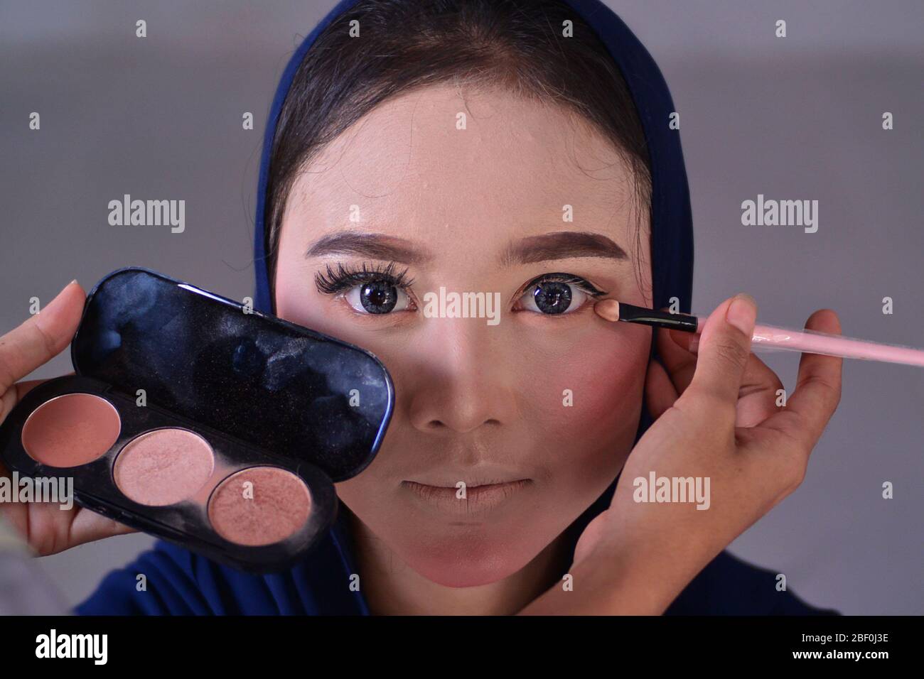 An aceh woman applies make up on her friend's face during the training.  Women in Aceh learn how to apply good makeup during a makeup training in  Blangpidie. Home cosmetology business in