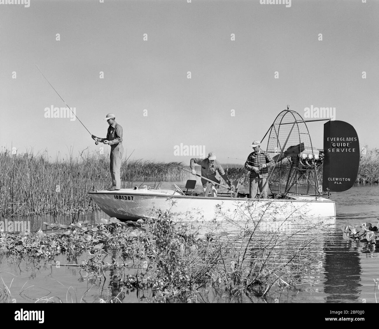 1950s THREE MEN ONBOARD AIR BOAT LARGEMOUTH BASS SPORT FISHING ON VACATION TRIP LAKE OKEECHOBEE EVERGLADES CLEWISTON FLORIDA USA - a2659 HAR001 HARS FRIENDSHIP FULL-LENGTH PERSONS SCENIC UNITED STATES OF AMERICA MALES HOOK TRANSPORTATION B&W NORTH AMERICA CATCHING FREEDOM GOALS NORTH AMERICAN TIME OFF WIDE ANGLE TOUR SKILL ACTIVITY AMUSEMENT ADVENTURE HOBBY LEISURE CUSTOMER SERVICE TRIP INTEREST GETAWAY EXCITEMENT HOBBIES KNOWLEDGE LOW ANGLE PARKS RECREATION TOURIST PASTIME BASS REEL PLEASURE ON OPPORTUNITY HOLIDAYS OCCUPATIONS SOUTHERN CONNECTION EVERGLADES GUIDED CONCEPTUAL GUIDE GUIDES Stock Photo