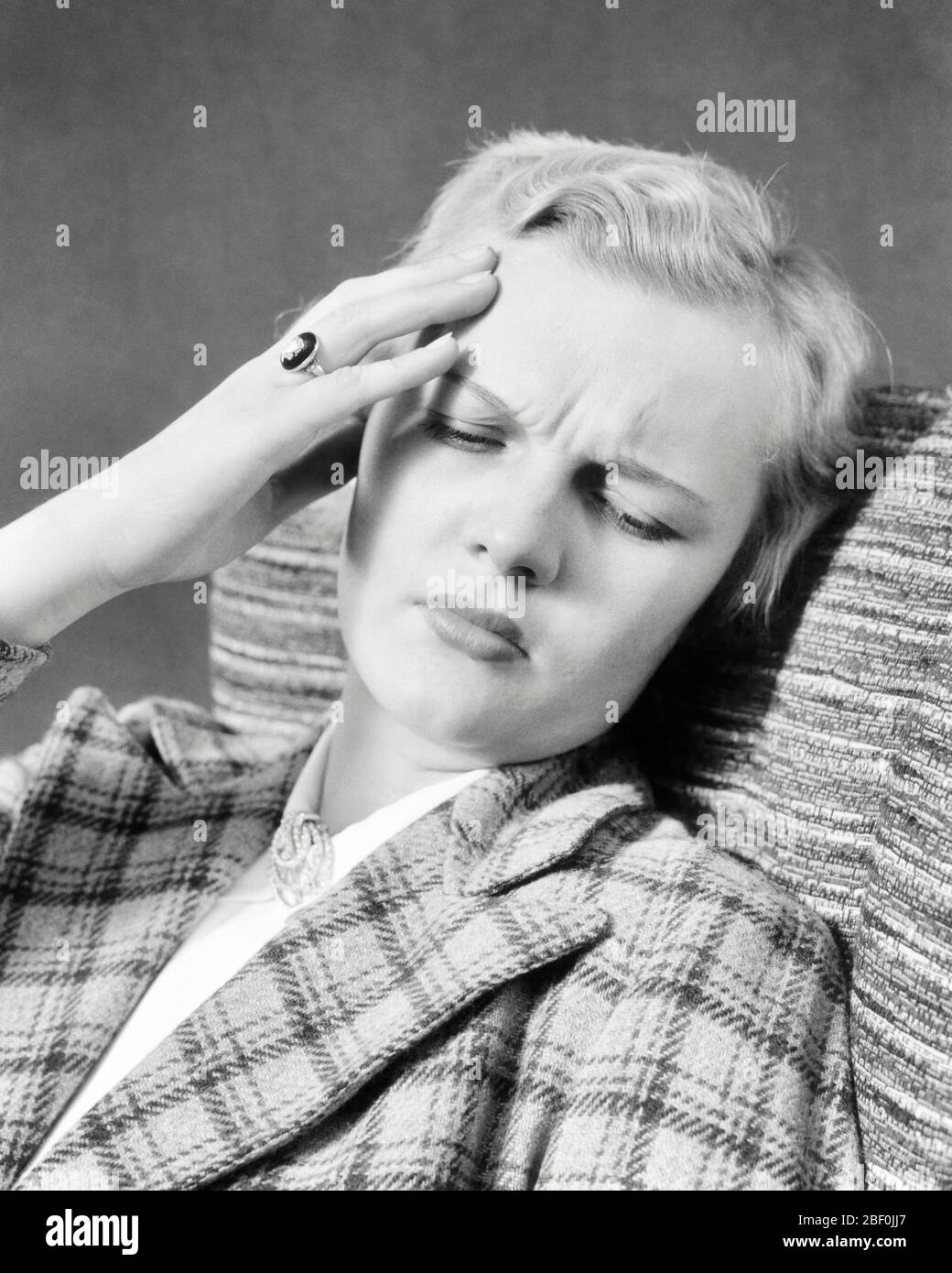 1940s DISTRESSED BLOND WOMAN HAND TO HER FOREHEAD PAINED EXPRESSION EYES CLOSED SUFFERING HEADACHE PAIN - a4180 HAR001 HARS LADIES PERSONS FOREHEAD NERVOUS AILMENT HEADACHE TROUBLED B&W CONCERNED SADNESS HEALTHCARE ANXIETY SUFFERING PREVENTION HEAD AND SHOULDERS DISTRESSED HEALING DIAGNOSIS DESPAIR HEALTH CARE IMPAIRMENT MOOD TREATMENT MENTAL HEALTH GLUM PAINED PANORAMIC POOR HEALTH TENSION AILING EMOTION EMOTIONAL EMOTIONS MID-ADULT MID-ADULT WOMAN MISERABLE SINUS BLACK AND WHITE CAUCASIAN ETHNICITY DISEASE EYES CLOSED HAR001 MENTAL ILLNESS OLD FASHIONED Stock Photo
