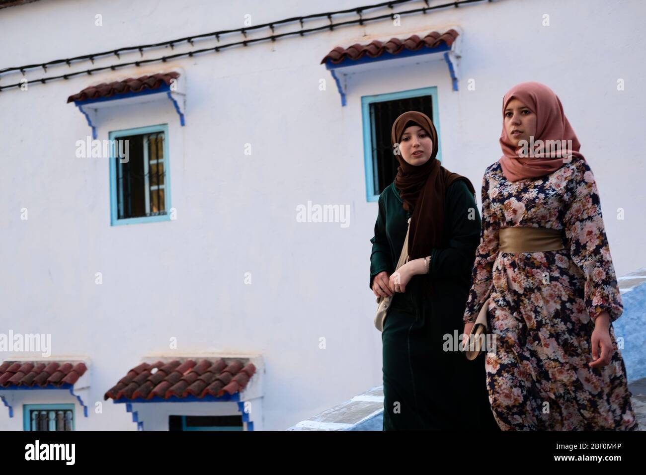 Chefchaouen, northern Morocco, 10th June 2016. Two Moroccan girls walk and talk on one of the city streets. Stock Photo