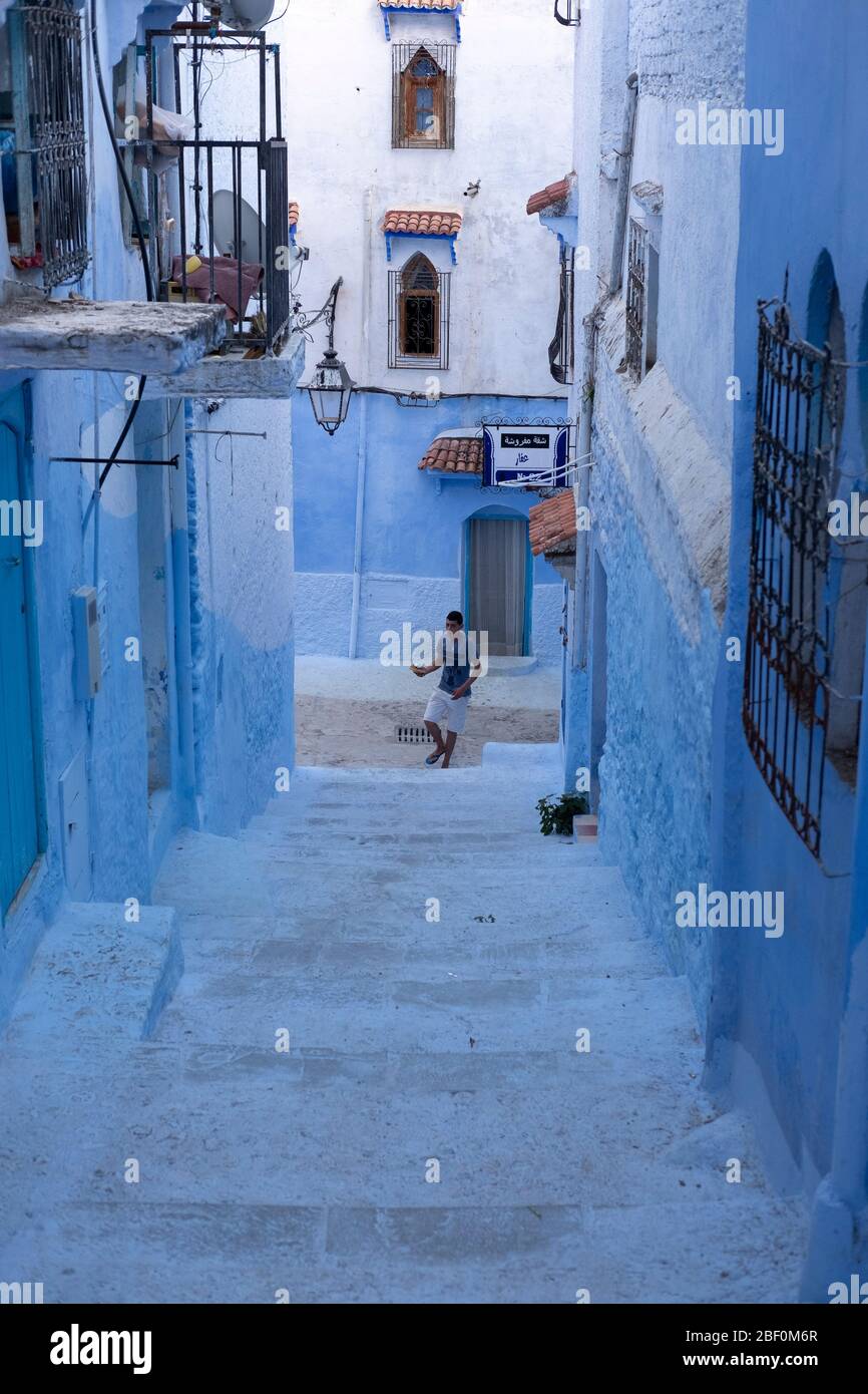 Chefchaouen, northern Morocco, 10th June 2016. A young man runs up the steps of a street in the old city, the blue city. Stock Photo