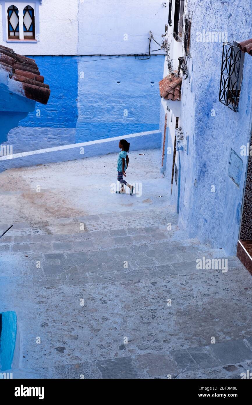 Chefchaouen, northern Morocco, 10th June 2016. A child plays in front of the door of his house in the blue city. Stock Photo