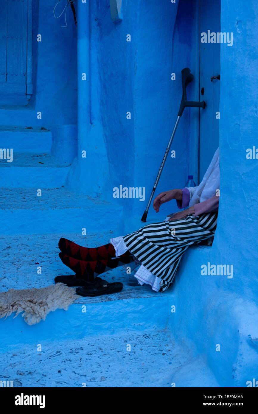 Chefchaouen, northern Morocco, June 10, 2016. An elderly woman, in traditional Moroccan dress, rests at the door. Stock Photo