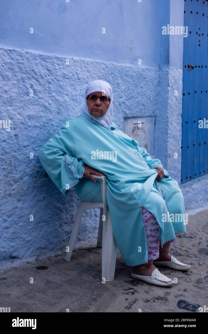Chefchaouen, northern Morocco, June 10, 2016. A lady in traditional Moroccan dress, looks at passersby at the door. Stock Photo