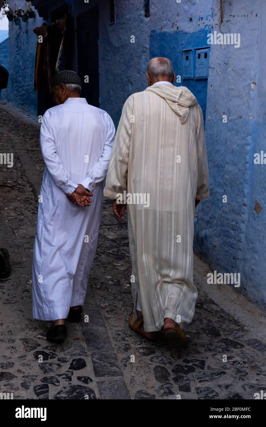 Chefchaouen, northern Morocco, June 10, 2016. Two elders, in traditional Moroccan dress, walk on one of the streets of the blue city. Stock Photo