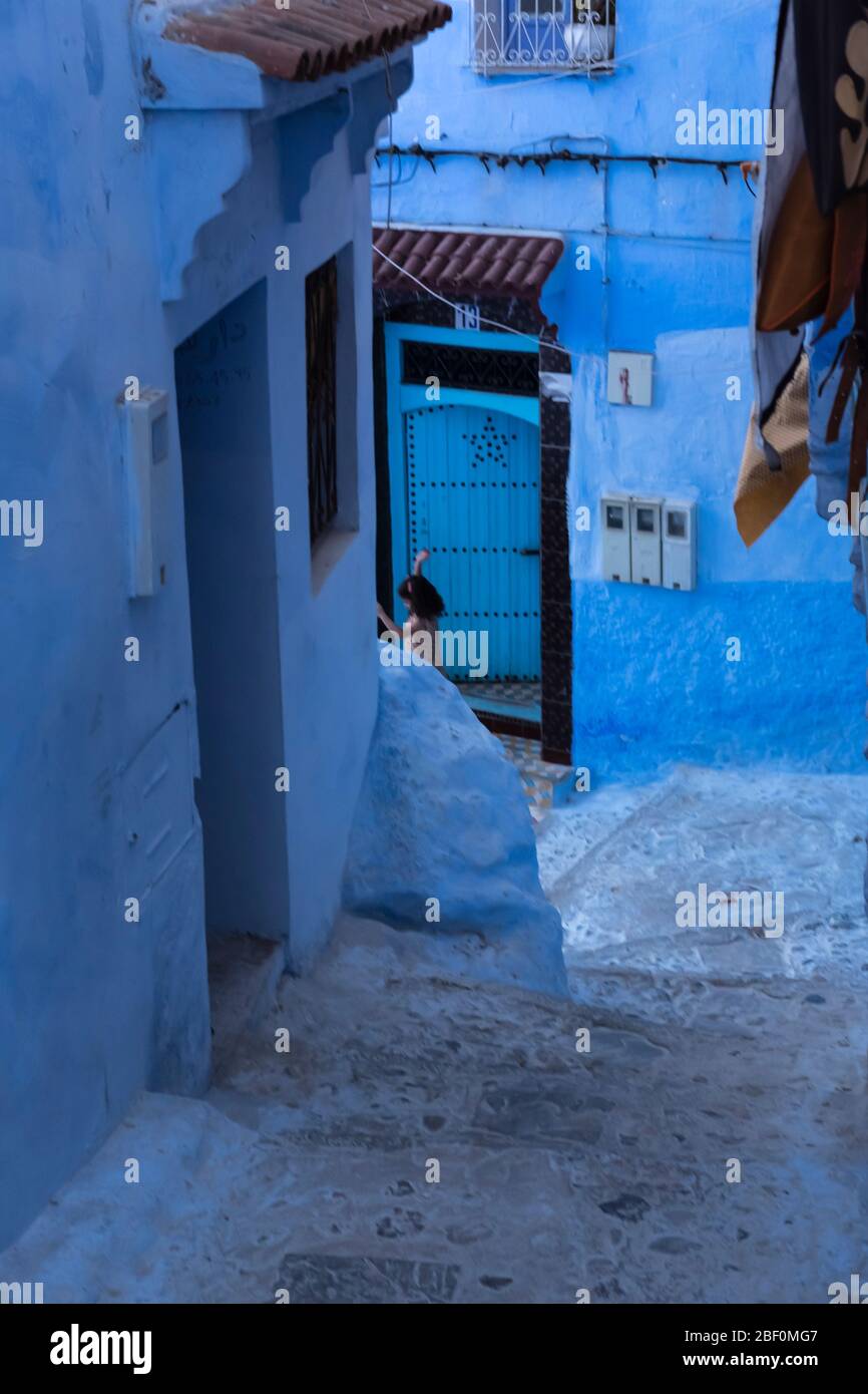 Chefchaouen, the blue city, northern Morocco, June 10, 2016. A child outside his house, plays. Stock Photo