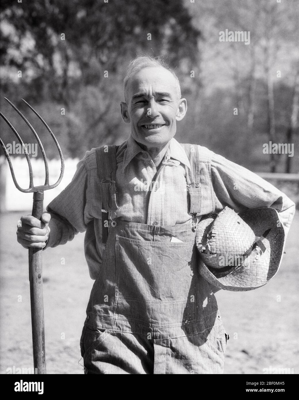 1930s SENIOR MAN FARMER PORTRAIT STANDING HOLDING STRAW HAT AND