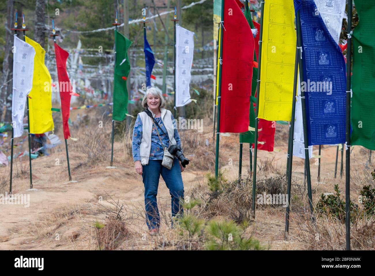 Bhutan, Thimphu. Prayer flags on mountain top at the Sangaygang Geodetic Station. Female tourist hiking on trail. Stock Photo